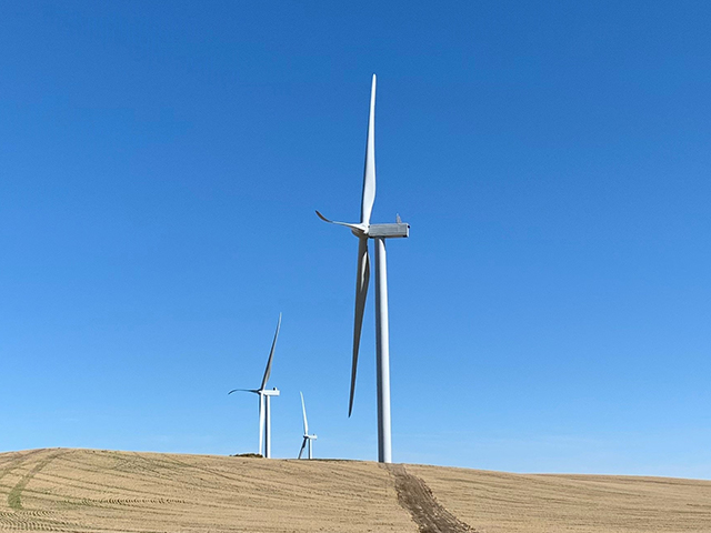 An up close image of the side of a wind turbine, with a blue sky behind.