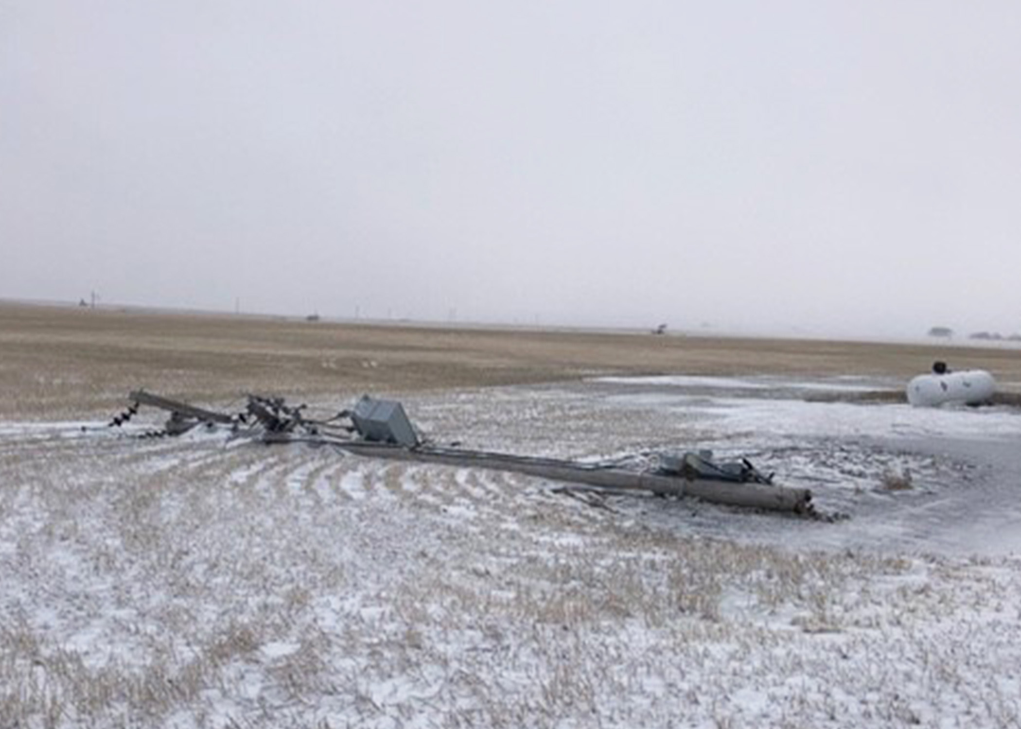 Power pole laying on a prairie field