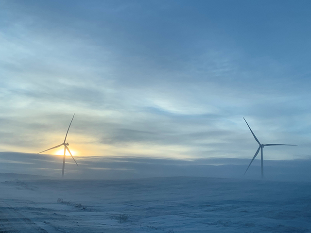 The top of two wind turbines peaking out of clouds.